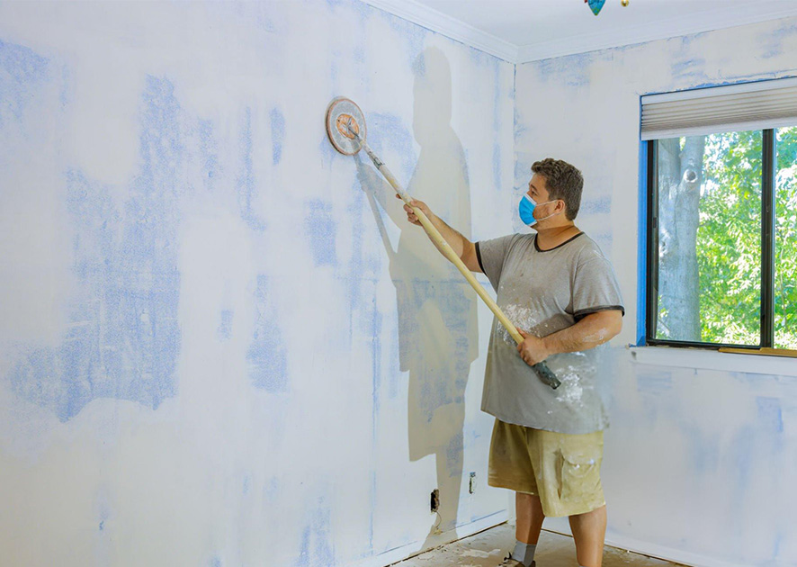 using tool to sand drywall in a ventilated room.
